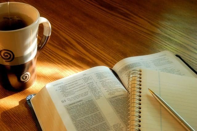 A cup of coffee and an open book on the table.