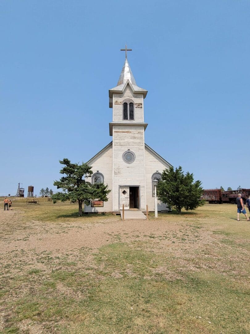 A white church with a steeple and clock on the top.