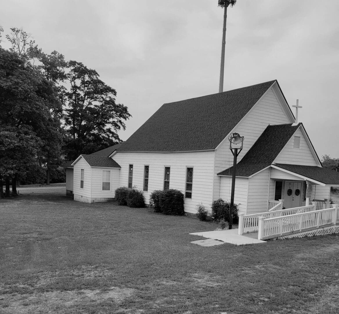 A black and white photo of a church with a fence.