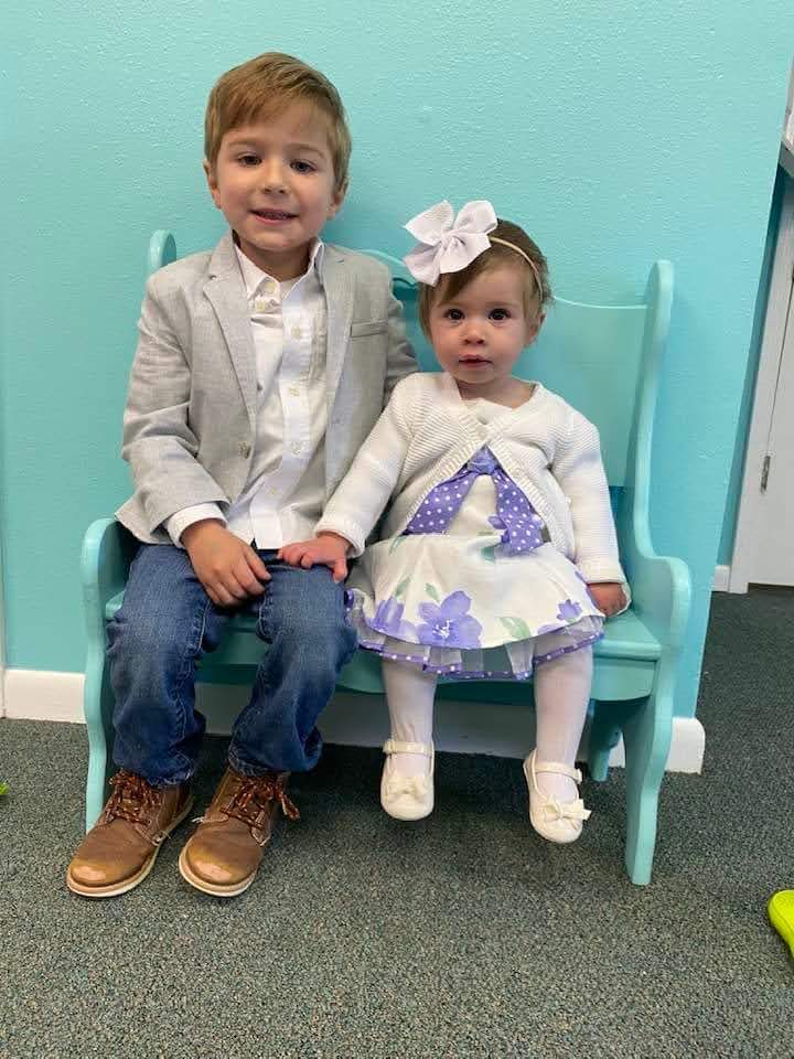 A boy and girl sitting on a bench.