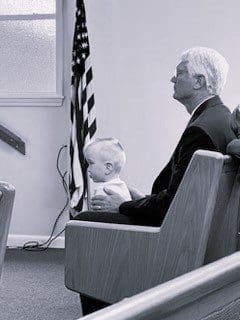 A man sitting in a church with a baby.